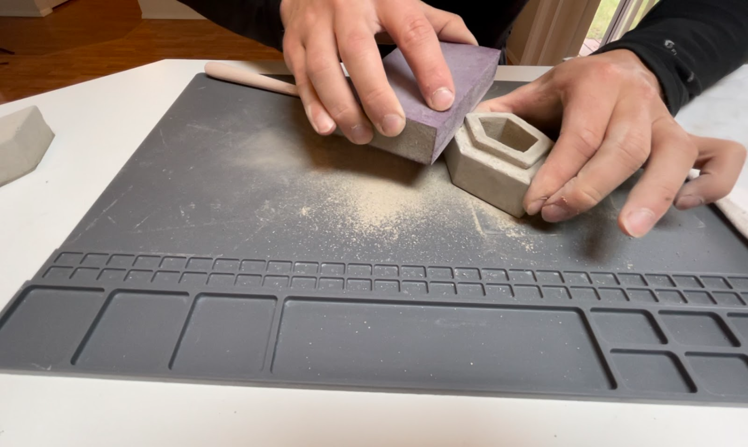 Sanding concrete hollow planter with 220 grit sandpaper block.