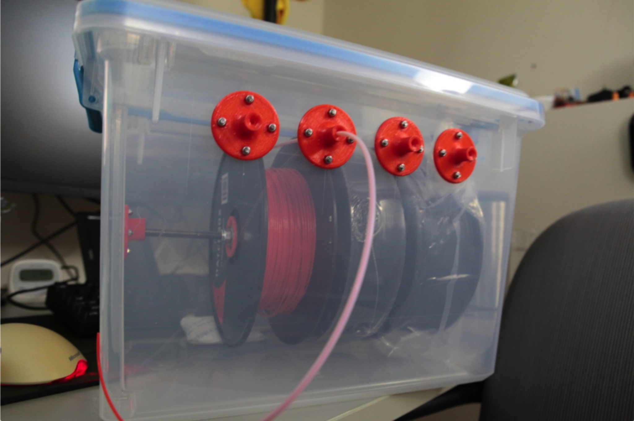 A DIY filament dry box made from a clear, airtight plastic bin, holding several spools and allowing filament to be fed directly to a 3D printer.