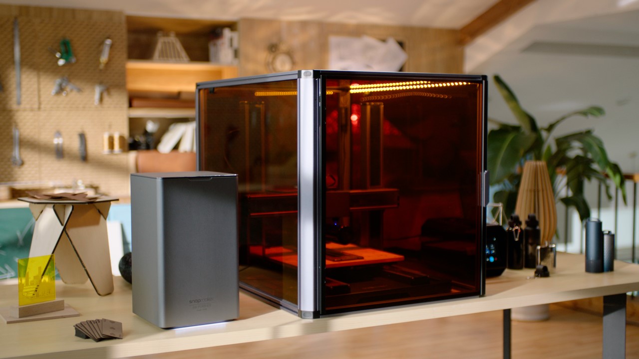 The Snapmaker Artisan 3-in-1 3D printer with its protective enclosure sits on a workbench, showing an example of a feature-rich machine for beginners.