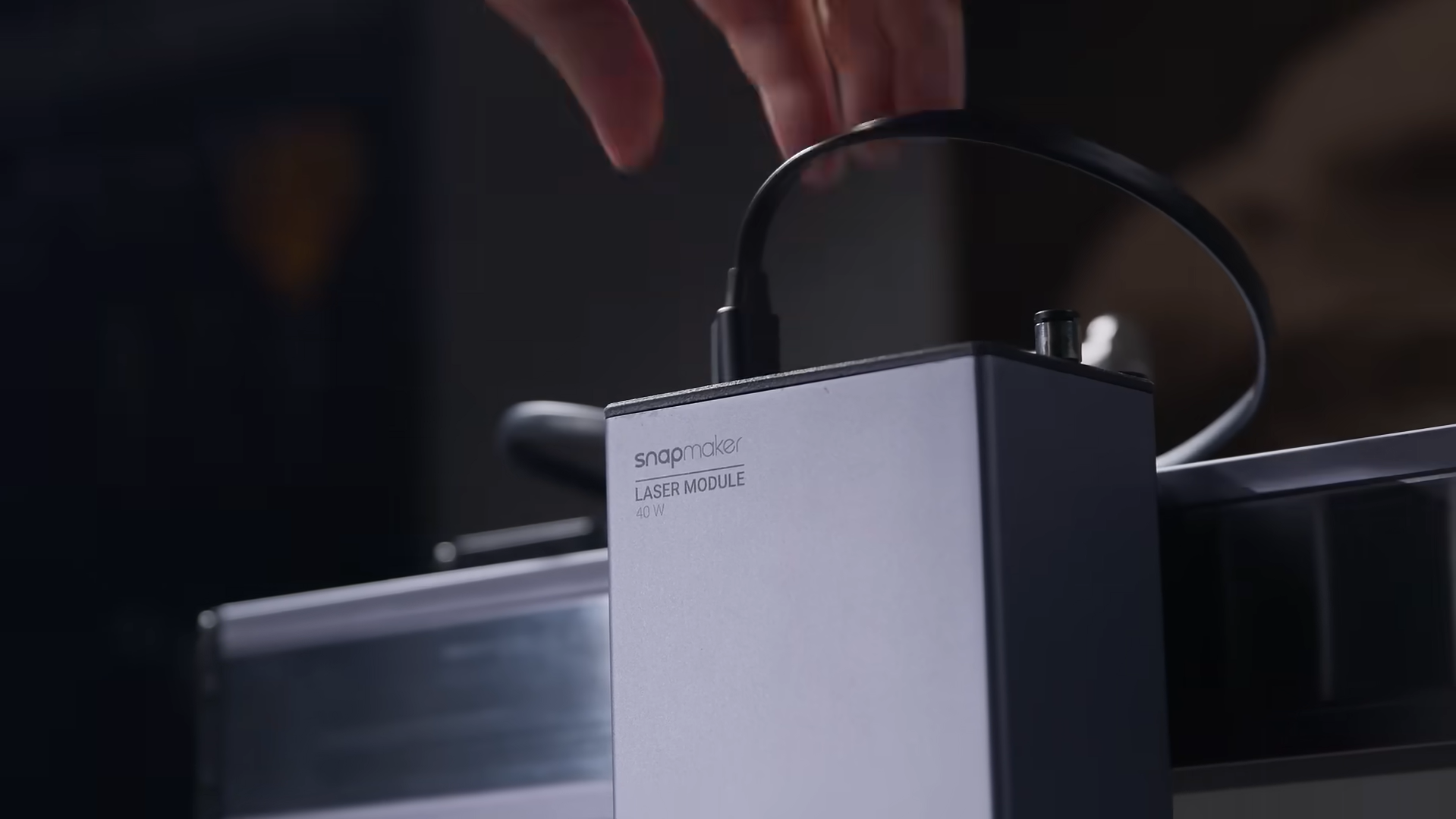 Close-up of a hand installing or adjusting the module on a versatile modular laser engraving and cutting machine.