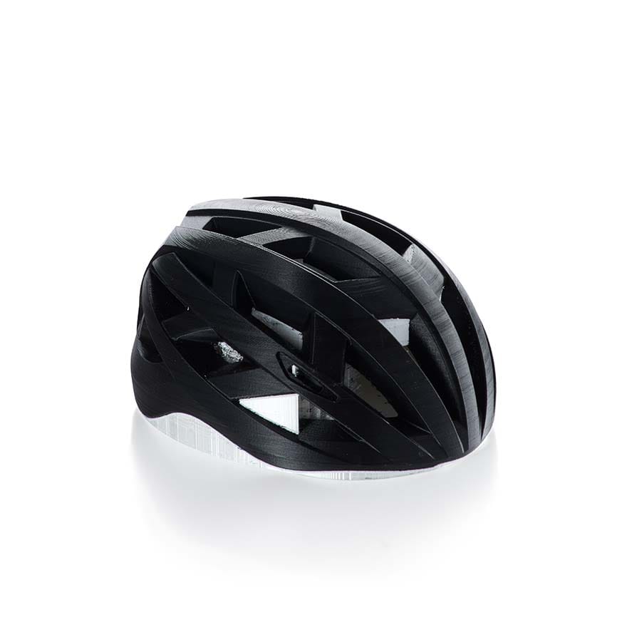 A black 3D printed bicycle helmet with a white inner layer, illustrating how infill patterns and strong walls create durable and impact-resistant parts.