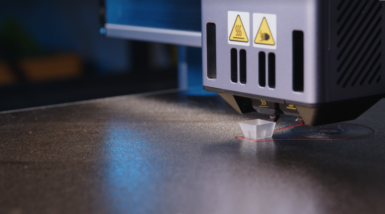 A close-up of  the two nozzles on a Fixed Dual Nozzle print head extruding filament, a common system for two-color 3D printing.