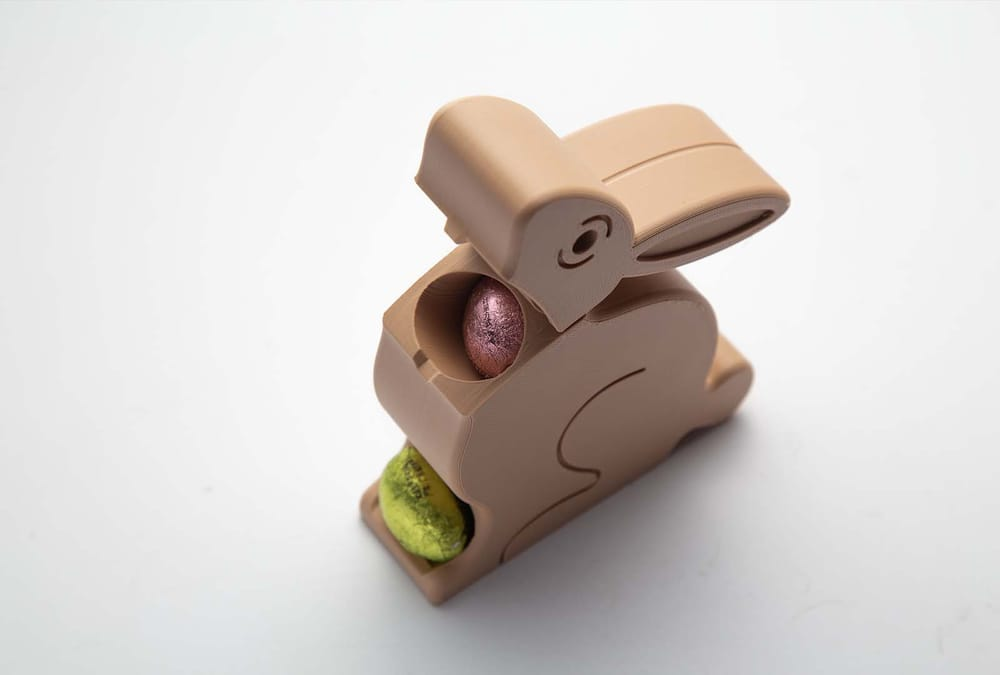 Two easy-to-print 3D printed bunny figures holding chocolate eggs, a fun project for beginners.