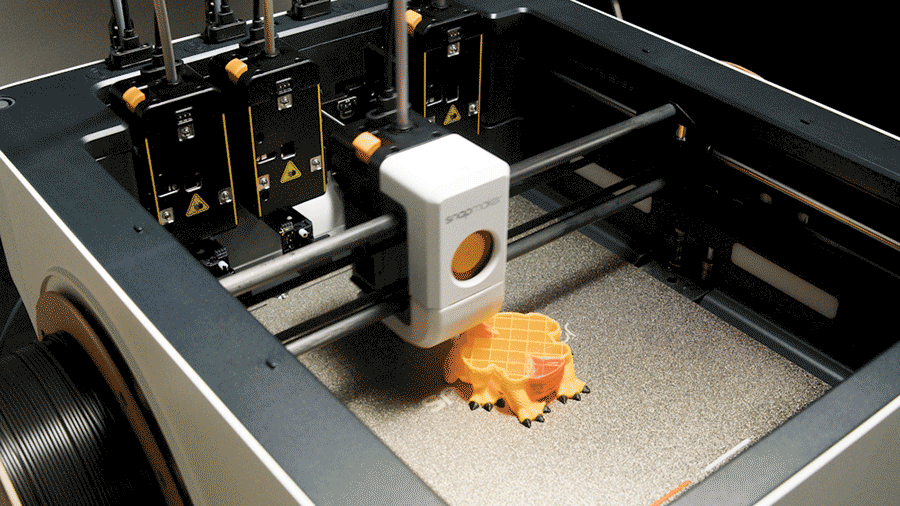 A Tool Changer 3D printer prints an object with one active tool head while three other extruders are parked, showcasing the automated multi-tool process.