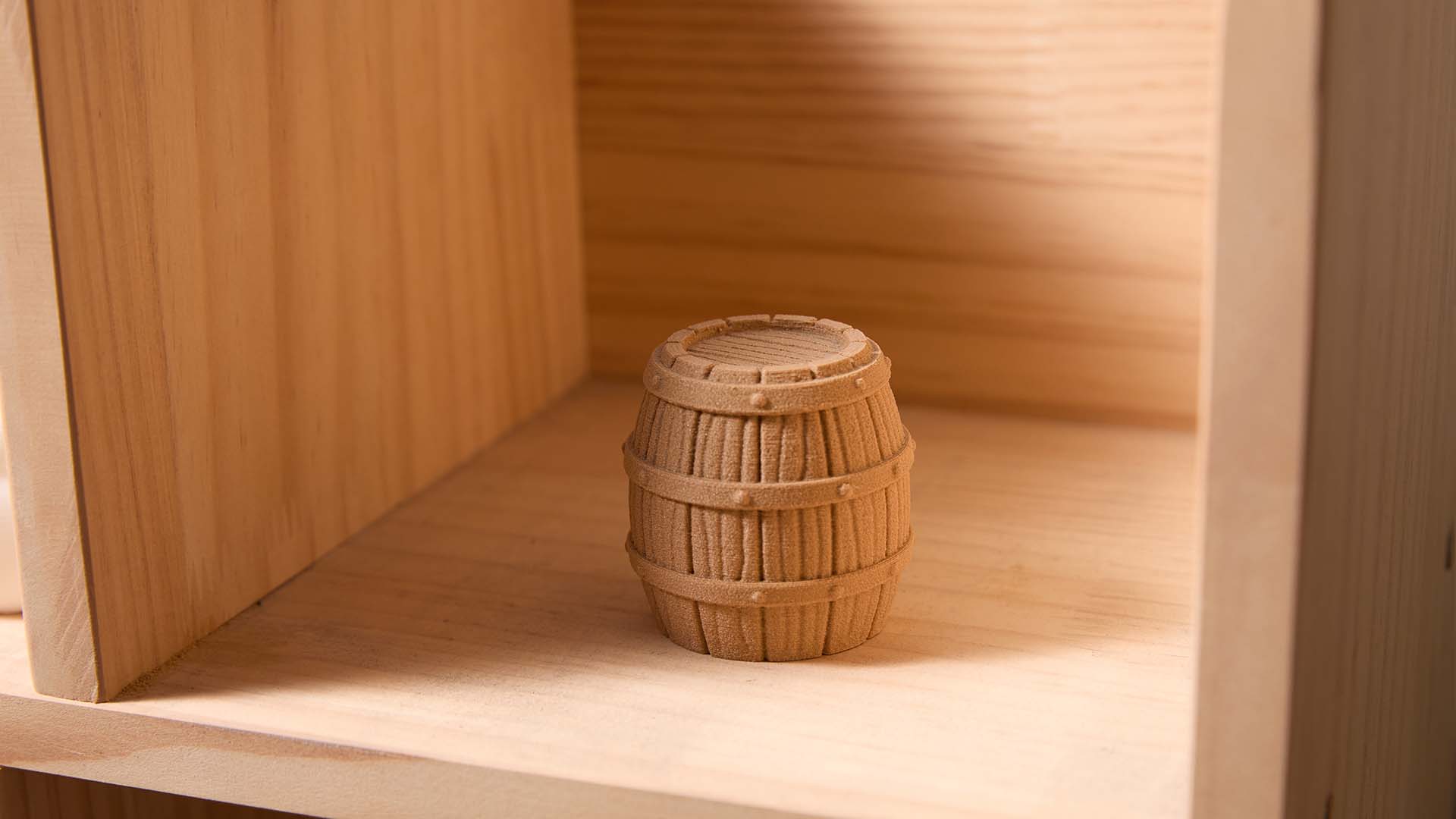 A 3D printed rustic wooden barrel with a realistic wood grain texture, created using wood PLA filament and sitting on a shelf.