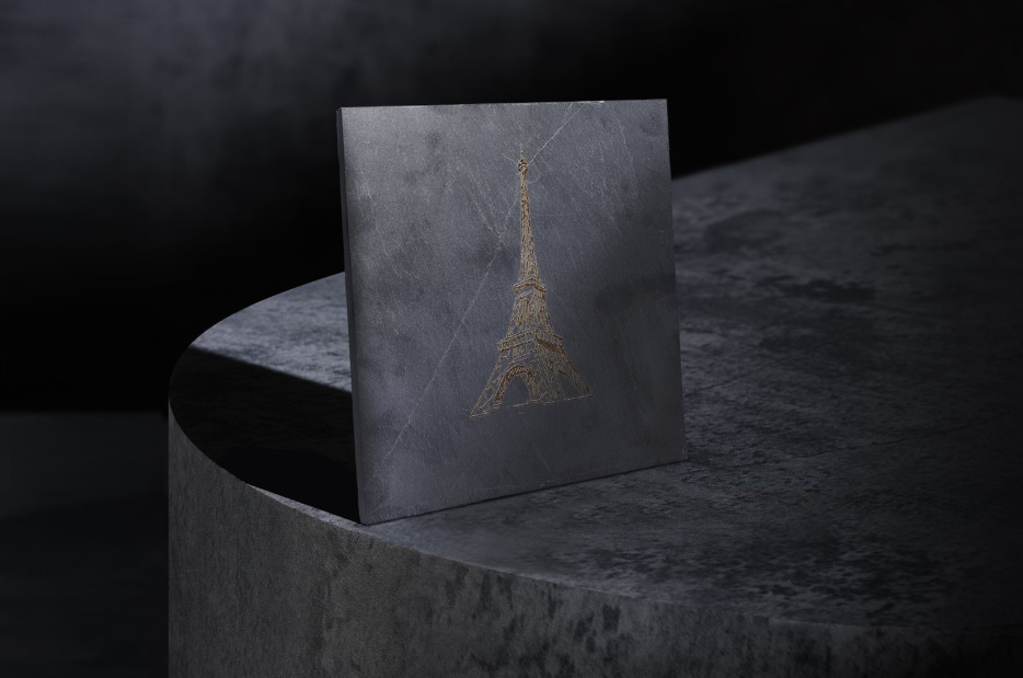 A square slate tile displaying a high-contrast, detailed laser engraving of the Eiffel Tower, showcasing a professional finish.