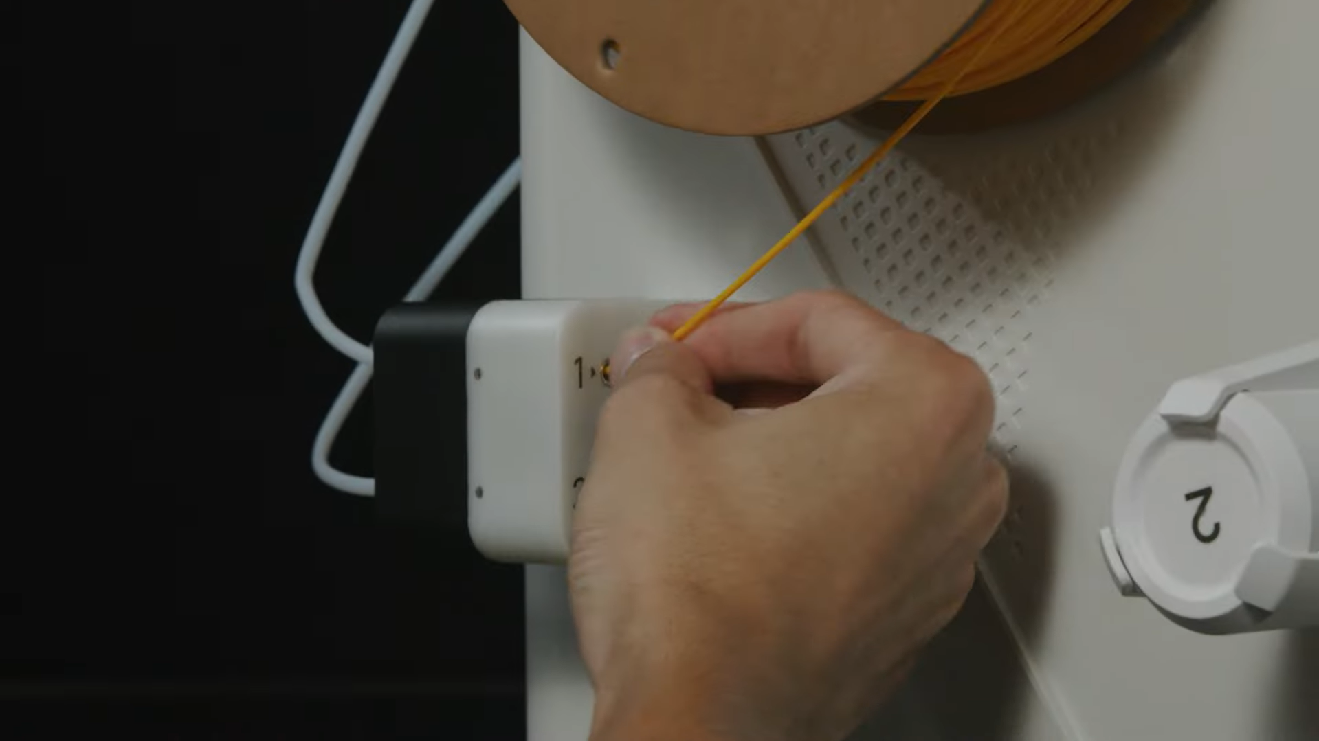 A user loads filament into the printer's material station, which uses automatic filament recognition to streamline the multi-material printing setup.