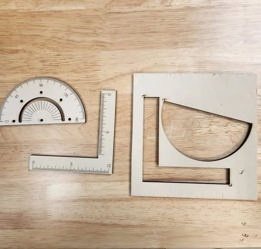 Several precise woodworking and geometry tools, including a protractor and rulers, are neatly arranged on a wooden surface.