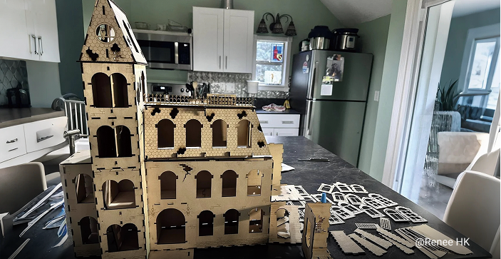A large, unfinished laser-cut wooden castle with multiple towers and windows, laid out on a kitchen counter with individual pieces visible.
