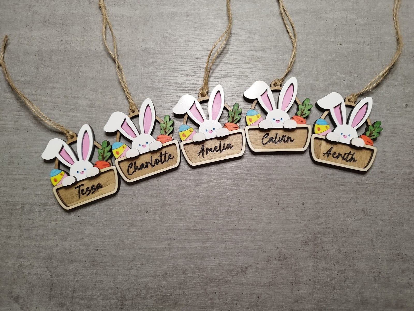 Five personalized laser-engraved wooden bunny name tags tied with twine, adding a customized, reusable keepsake element to a junk-free Easter basket.