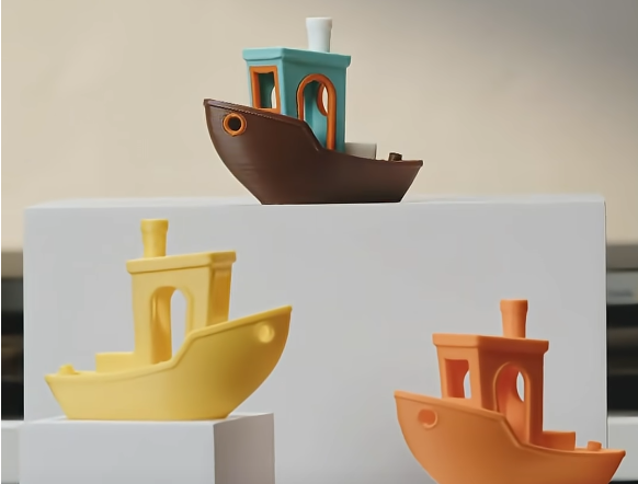 Multi-color 3D printed Benchy boats, examples of multi-material printing that require filament waste during color swaps.