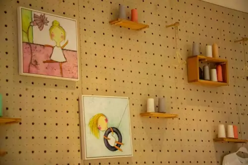 Standard 1/4-inch round hole pegboard wall with wooden shelves and decor, showing a snap-fit accessory setup for workspace organization.