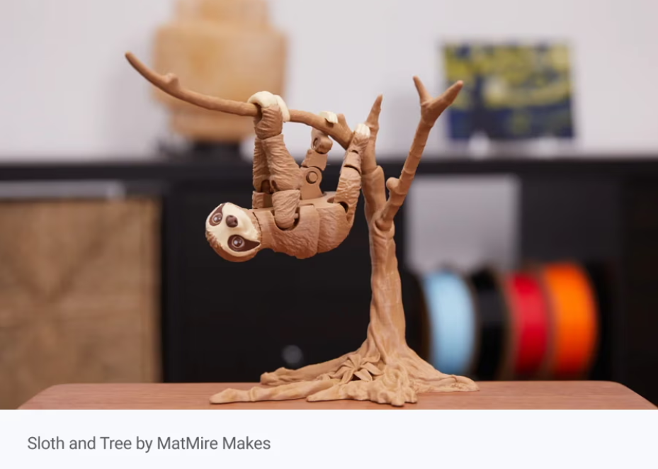 Articulated 3D printed sloth on a tree, a popular meme-inspired desk companion print.