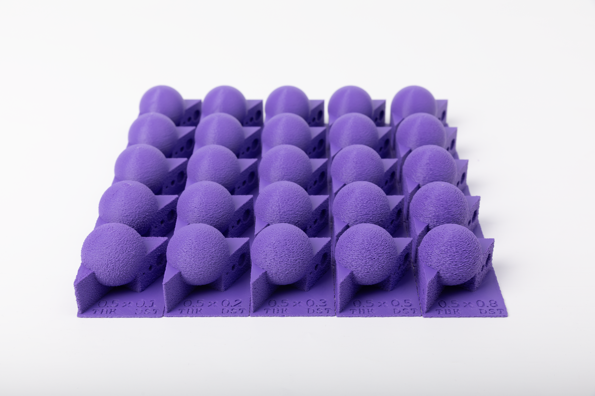 A large matrix of purple 3D printed test objects used to calibrate fuzzy skin settings and prevent hardware limits from ruining a print.