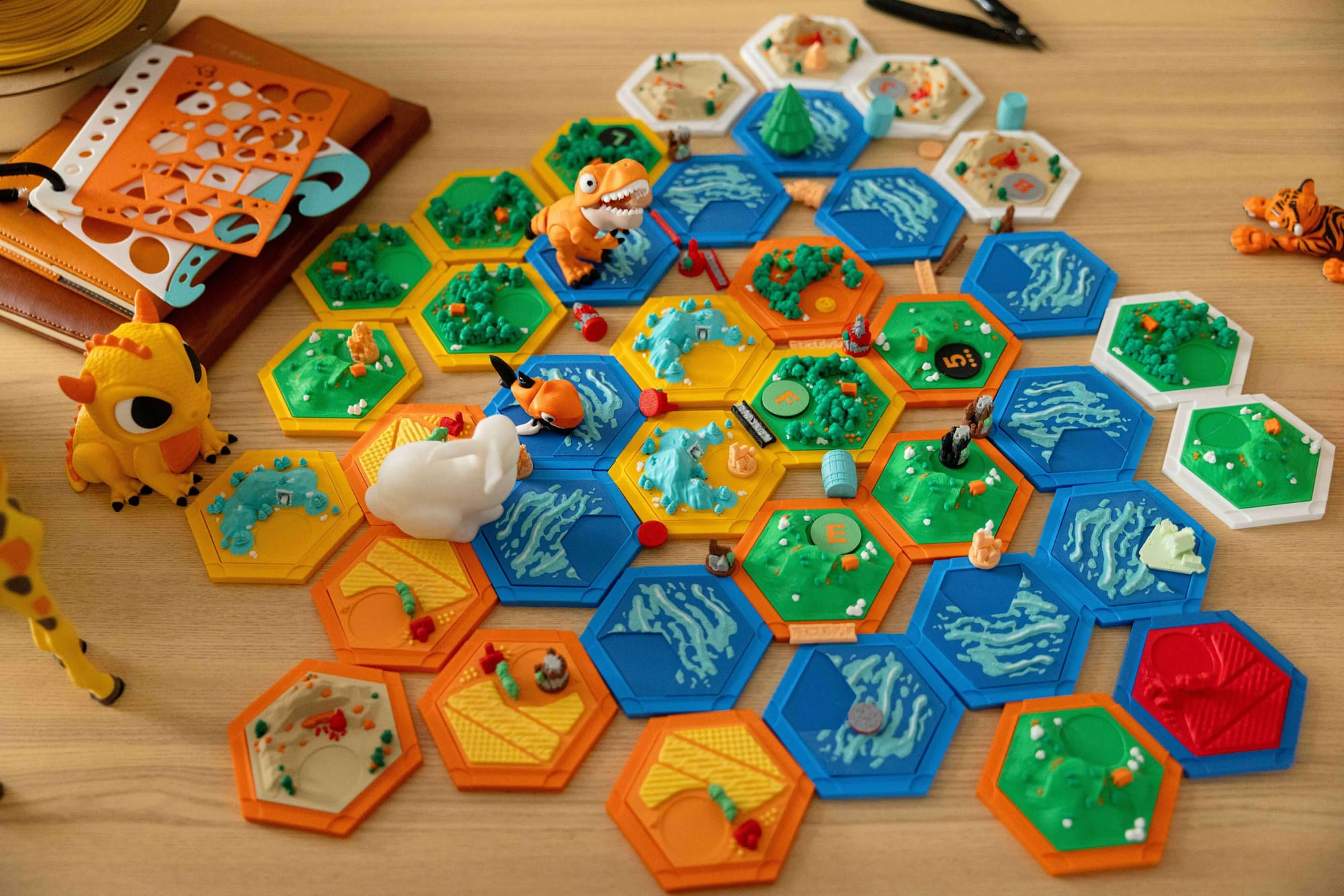 A top-down view of multi-color 3D-printed hexagonal terrain tiles and game pieces, demonstrating how color-contrasting models enhance K-12 STEM projects and interactive learning.