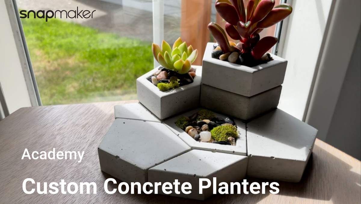 A close-up of several small, geometric concrete planters with succulents,