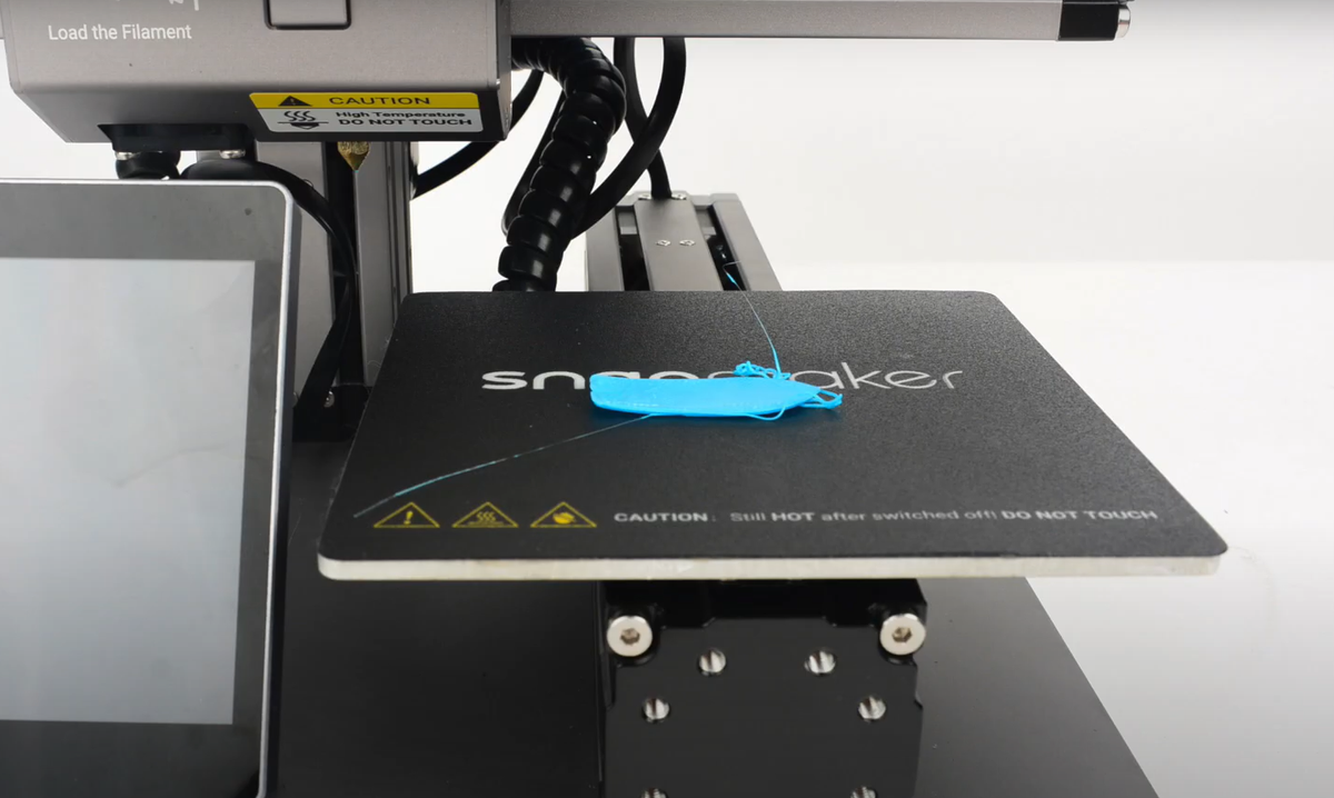 A failed light blue 3D print that has detached from the build plate, resulting in a tangled mess of filament that illustrates a bed adhesion problem.