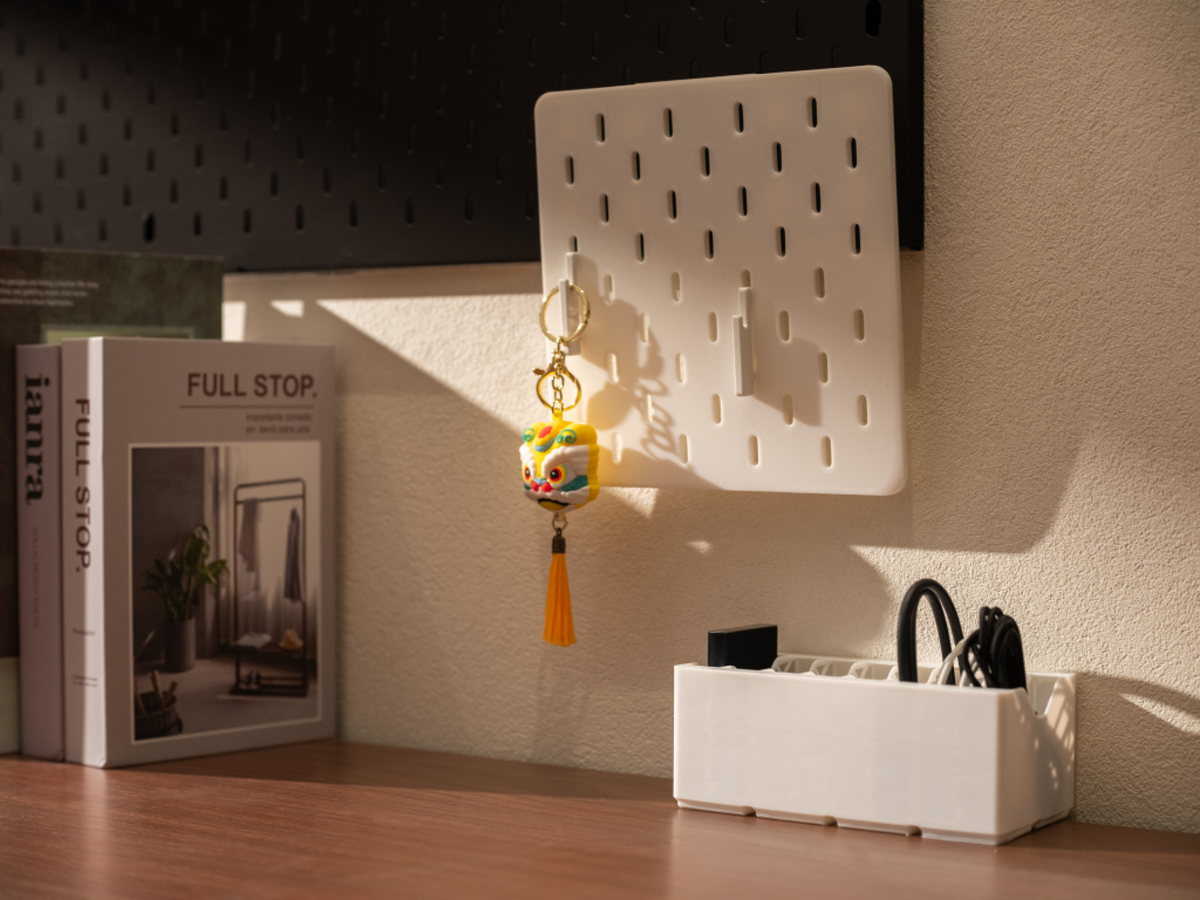 A sunlit desk showcasing a white 3D-printed wall pegboard and a matching horizontal organizer bin, demonstrating a hybrid vertical and horizontal storage setup.