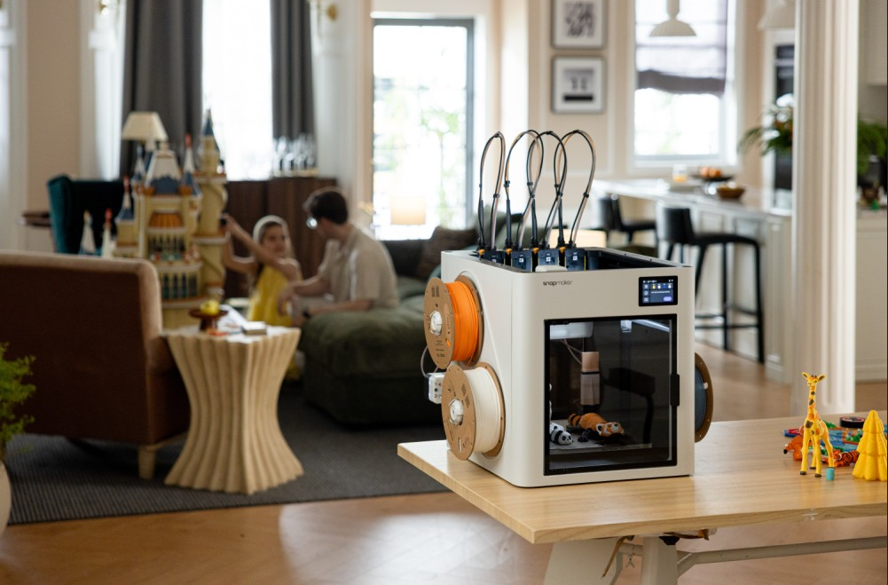 A fully-enclosed modern 3D printer operating in a family living room, demonstrating how accessible and integrated home 3D printing has become.