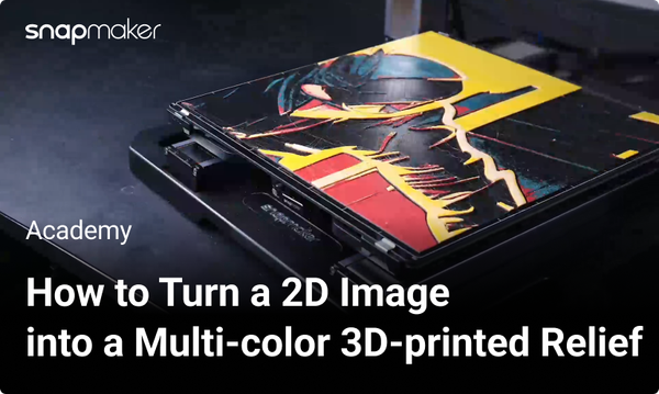 Image of a Snapmaker 3D printer with a multi-color 3D-printed relief on its print bed, featuring a vibrant design with red, yellow, and black layers.
