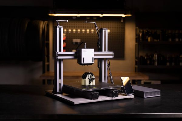 A modern dual extrusion 3D printer creating a two-color gear model, illustrating the capabilities of multi-material printing.