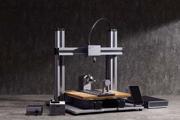 A Snapmaker CNC machine with a wooden worktable, equipped for precision milling, shown with a tablet and additional modules against a dark industrial background.