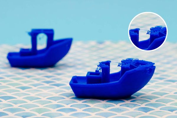 Two blue 3D-printed boats on a mermaid-scale patterned surface, with one showing stringing issues highlighted in a close-up inset, indicating a common 3D printing filament waste problem.