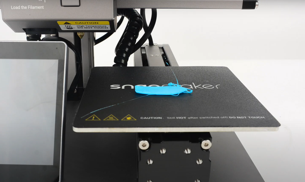 A failed light blue 3D print that has detached from the build plate, resulting in a tangled mess of filament that illustrates a bed adhesion problem.