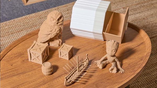 A collection of various 3D printed objects made with wood PLA filament, including Groot, a sailboat, and storage boxes, displayed on a wooden table.