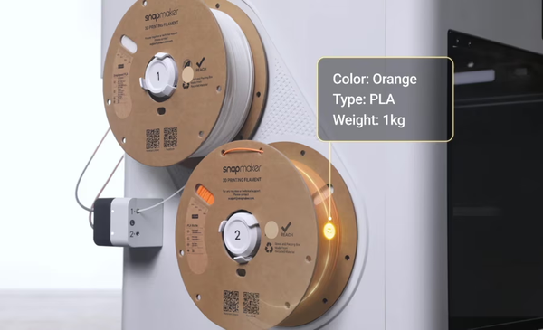 Two cardboard Snapmaker filament spools mounted on a 3D printer, with a digital callout displaying auto-detected material data like color and type for the orange PLA spool.