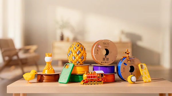 3D printed models and filament spools on a wooden table in a bright room.