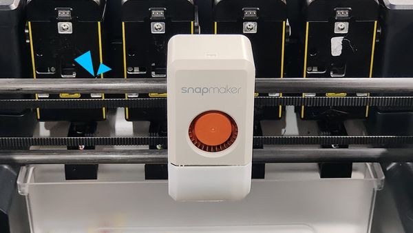 Close-up of a Snapmaker 3D printer’s print head on linear rails, highlighting the area where lubrication maintenance is needed.