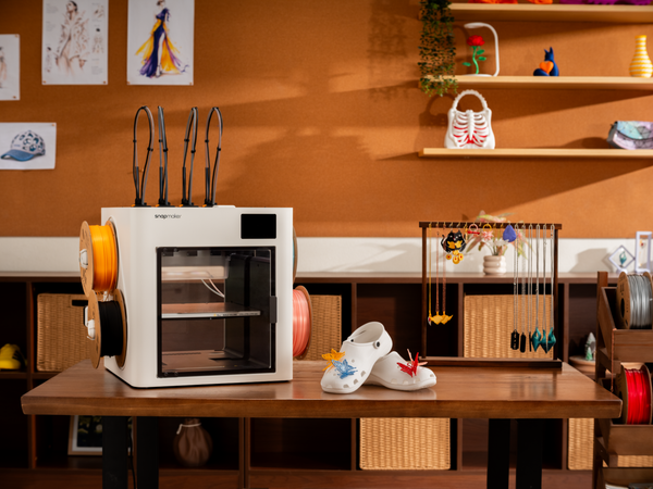 A 3D printer sits on a desk with a completed white TPU clog resting nearby to demonstrate a successful 3D printing project.