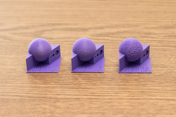 Three purple 3D printed test models displaying varying degrees of fuzzy skin thickness and point distance settings to demonstrate texture differences.