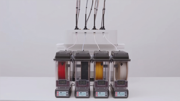 Four SnapDryer filament dry boxes displaying internal humidity levels and actively feeding a 3D printer to prevent moisture absorption during multi-color prints.