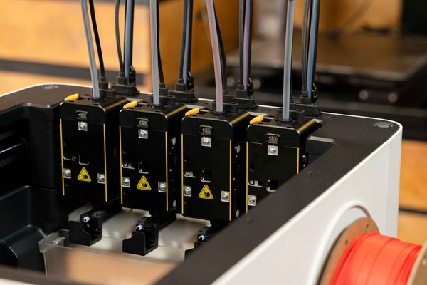 A close-up view of four independent print heads docked inside a Snapmaker 3D printer, demonstrating the tool-changing technology used to reduce filament waste during multi-color projects.