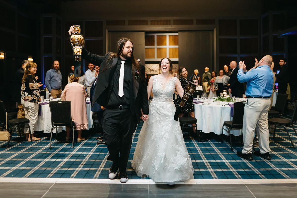 two people enter a wedding hold title belts