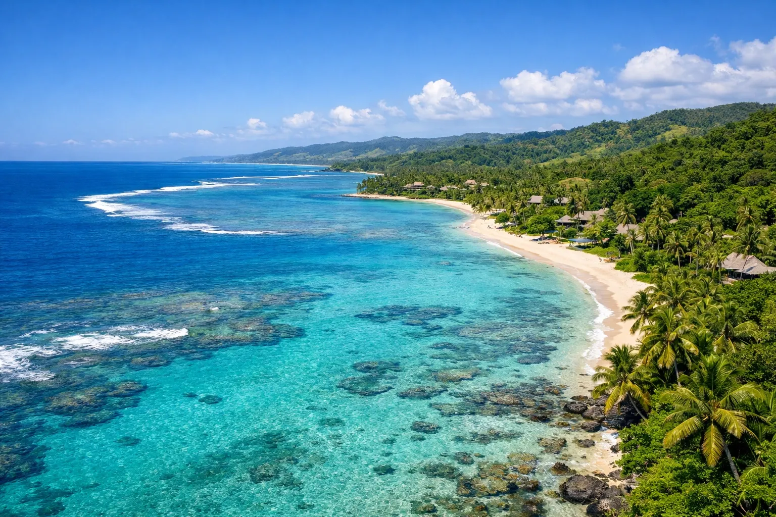 Wide shot of the Coral Coast, Fiji — aquamarine water, lush green tropical coastline.