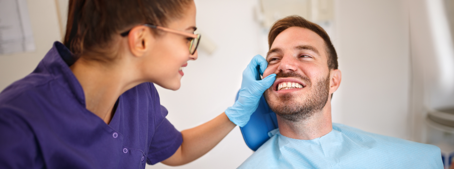 Eine Zahnärztin untersucht die Zähne eines Patienten.