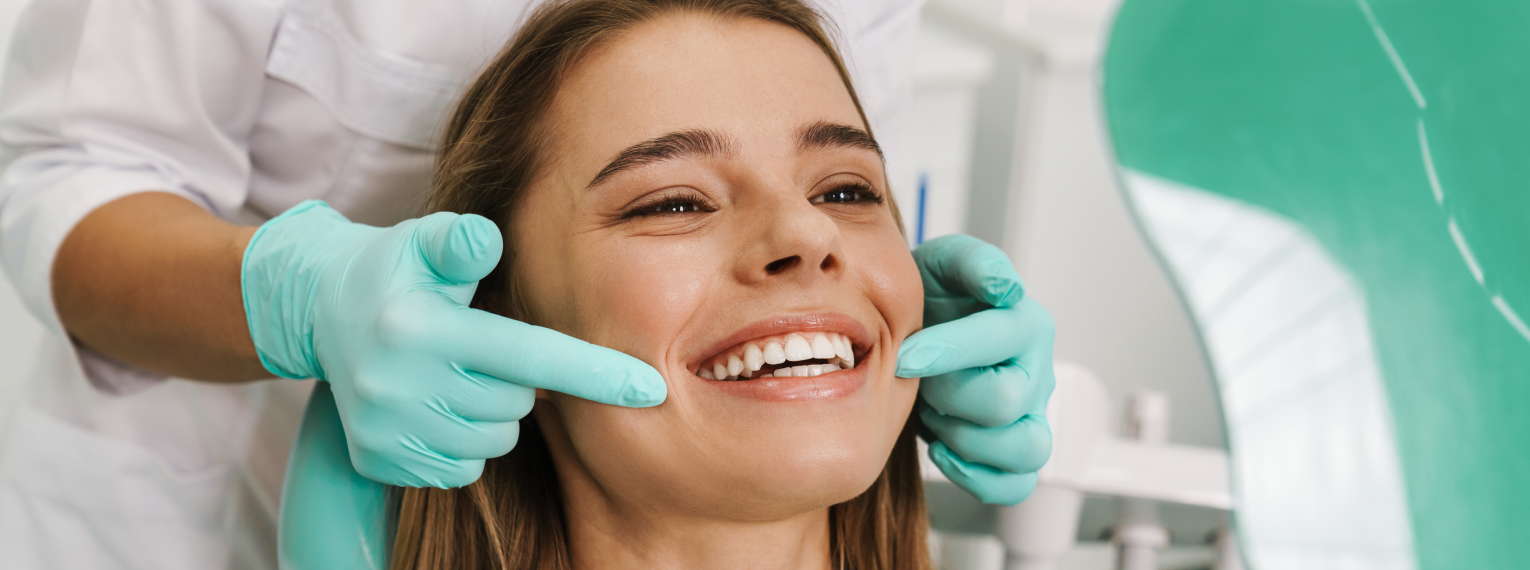 Eine lächelnde Frau wird beim Zahnarzt untersucht.