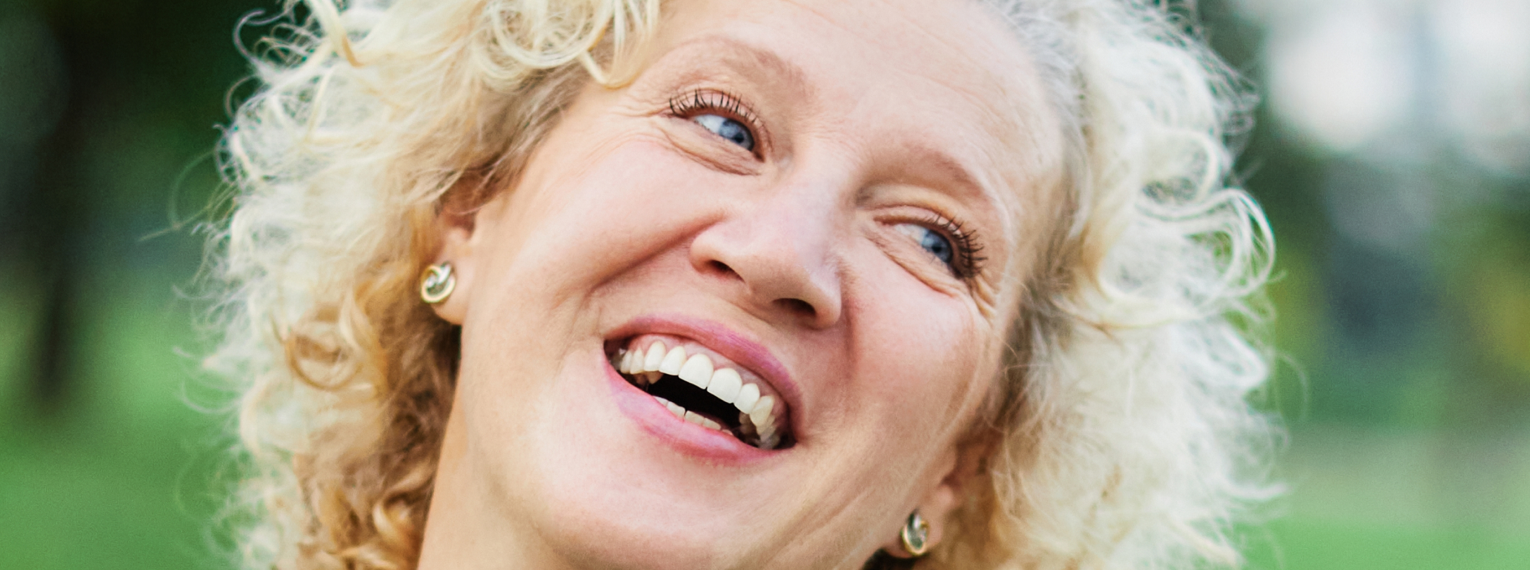 Eine Frau mit blonden Haaren lacht fröhlich.