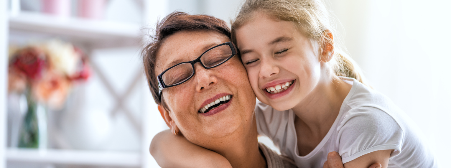 Eine Frau und ein Mädchen umarmen sich und lachen dabei.