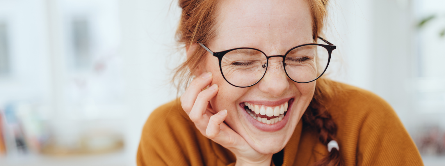Eine Frau lächelt mit strahlenden Zähnen nach einer professionellen Zahnreinigung.