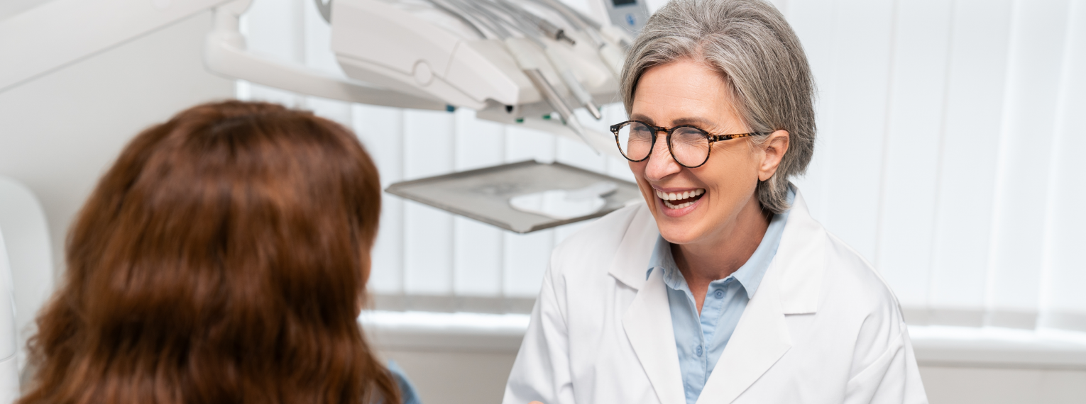 Eine Zahnärztin lächelt eine Patientin an.