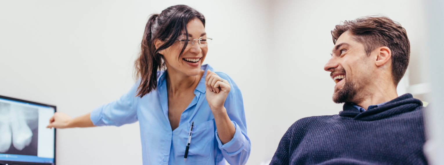 Eine Zahnärztin unterhält sich mit einem Patienten.