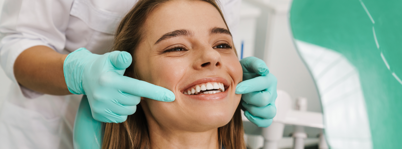 Eine lächelnde Patientin wird von einer Zahnärztin behandelt.