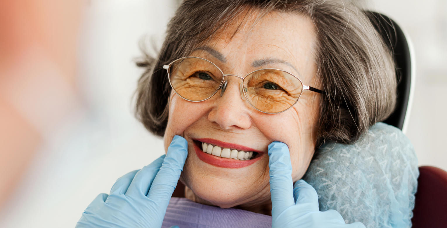 Eine Patientien beim Zahnarzt lächelt breit in die Kamera.