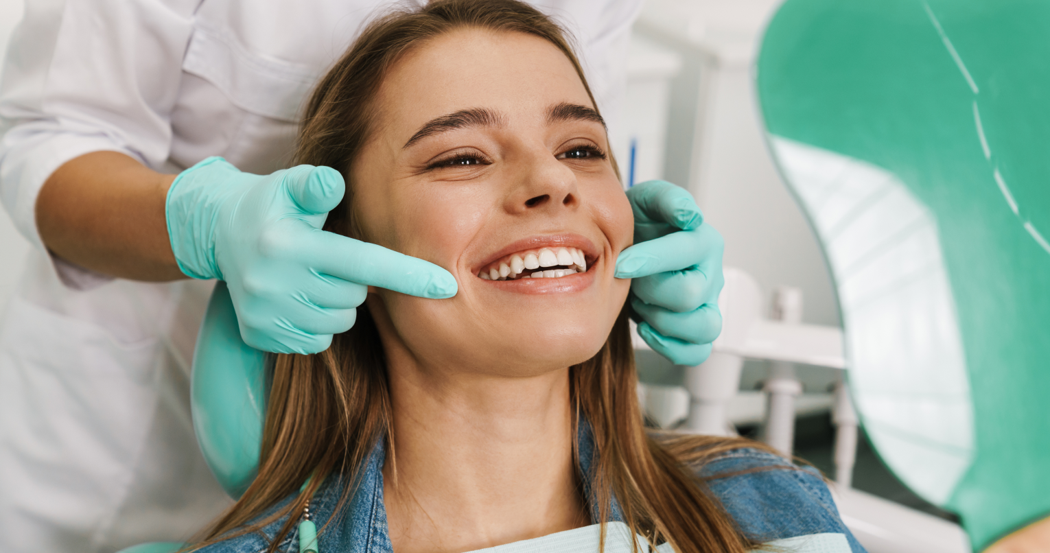 Eine lächelnde Patientin wird von einer Zahnärztin behandelt.