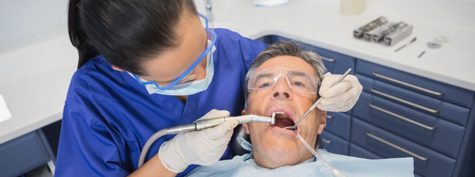 Eine Zahnärztin führt bei einem Patienten eine zahnärztliche Behandlung durch.