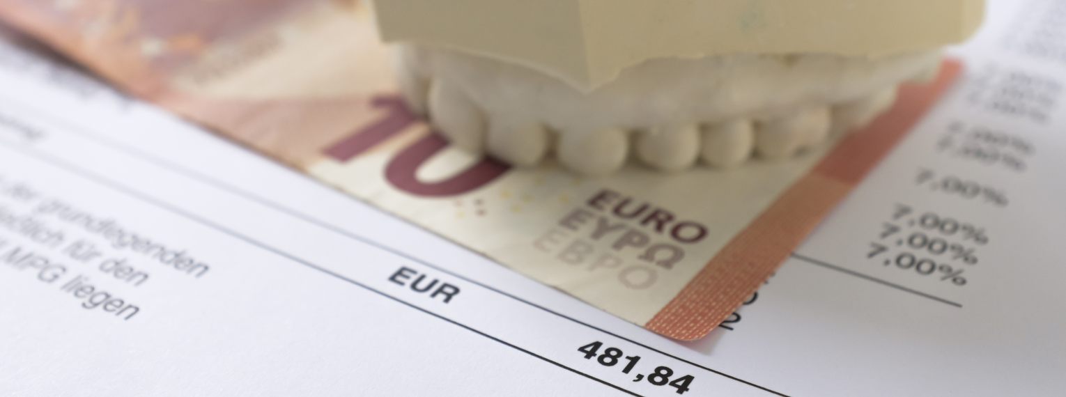 Eine Zahnprothese liegt auf einem 10-Euro-Schein und einer Zahnarztrechnung
